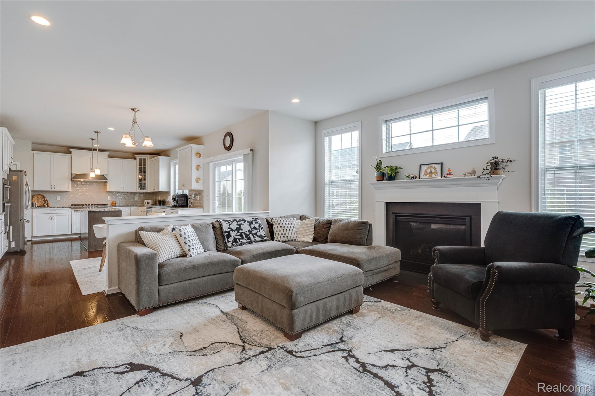 51011 Rockingham Drive Canton, MI 48188 - Photo 23 of 74 Living room with dark wood-style flooring, a glass covered fireplace, and hanging lights