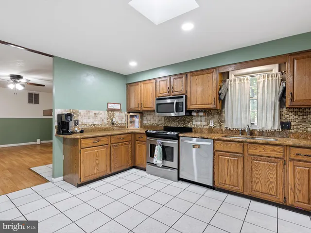 a kitchen with stainless steel appliances granite countertop sink stove top oven and cabinets