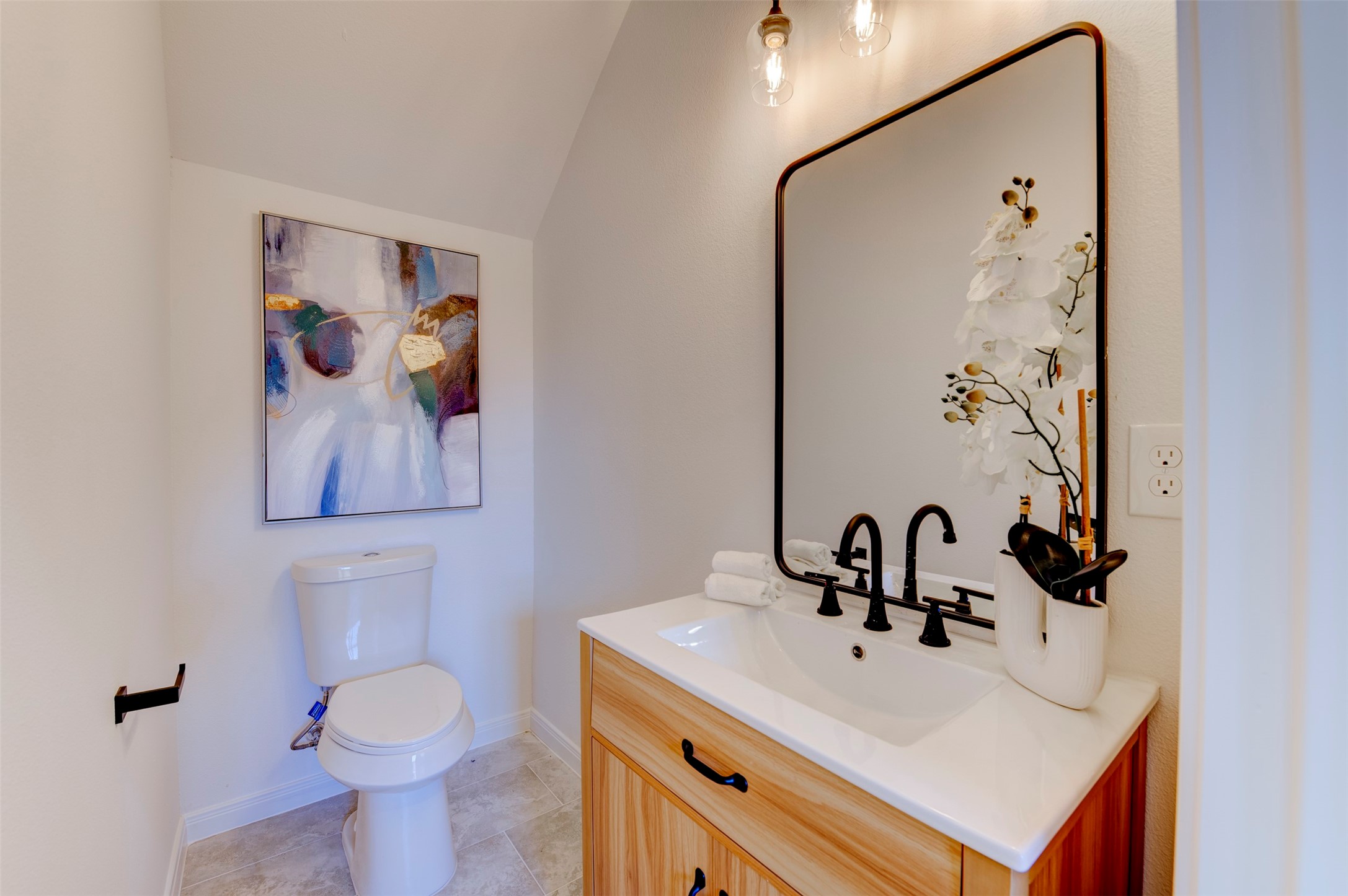 6807 Paris Street Houston, TX 77021 - Photo 3 of 50 First-floor powder bath with wood-tone vanity, white quartz countertop, matte black faucet, large black-framed mirror, pendant lighting, and vaulted ceiling detail.