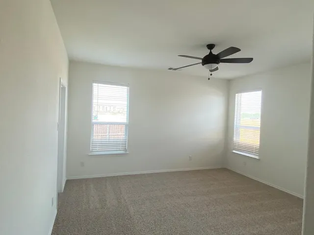 an empty room with windows and fan