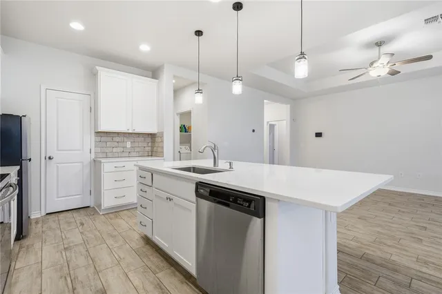 a large kitchen with kitchen island a stove a sink a center island and wooden floor