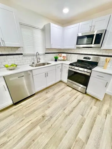 a kitchen with stainless steel appliances a stove a sink and white cabinets