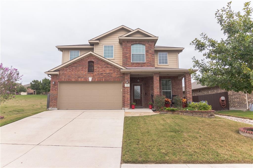 View of front of house with a front lawn, a porch, driveway, a garage, and brick siding