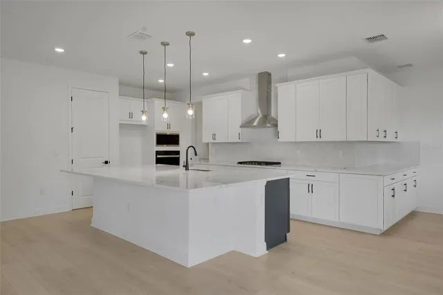 a large white kitchen with a large counter top and stainless steel appliances