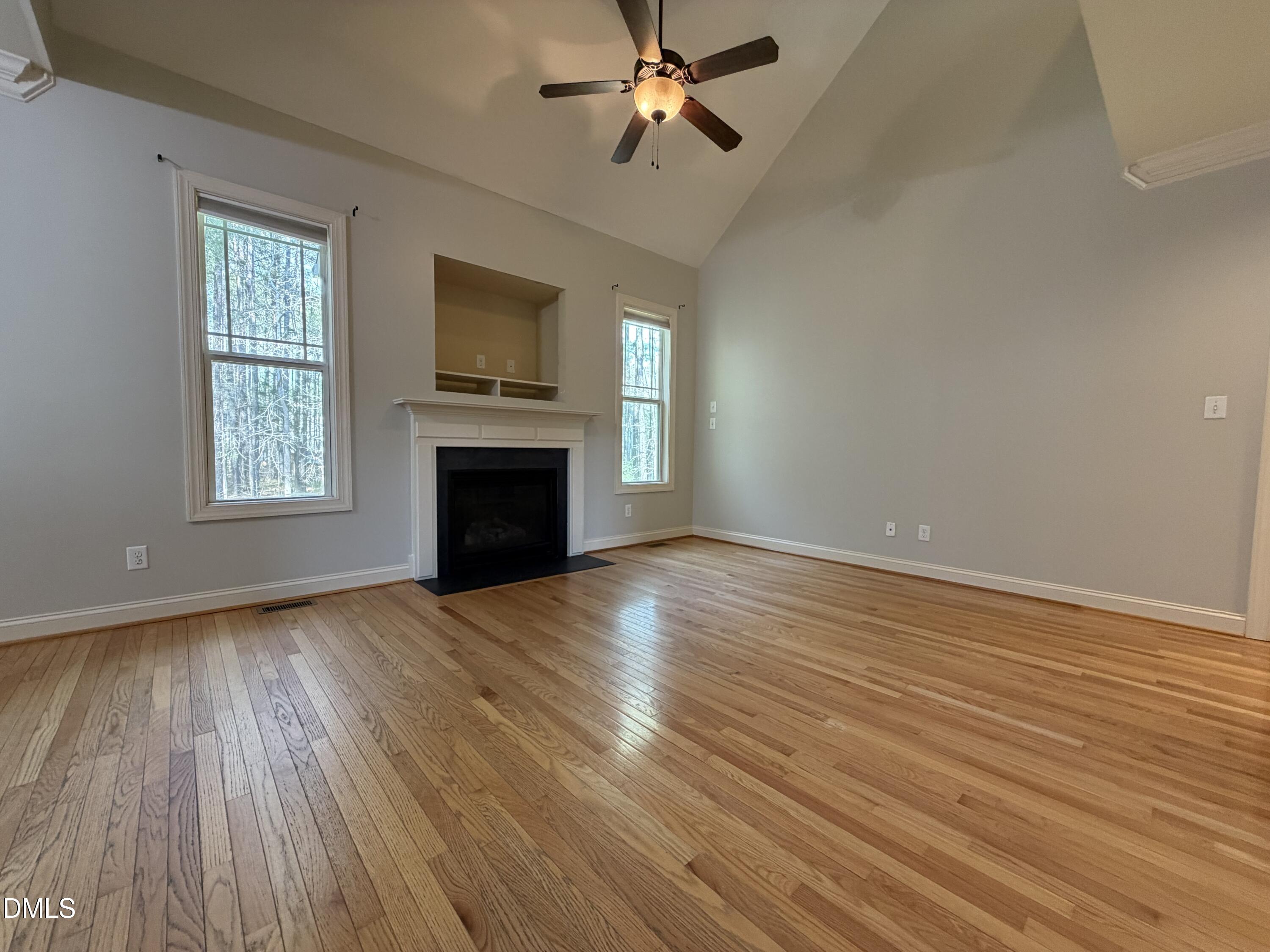 204 Blair Hills Road Wendell, NC 27591 - Photo 12 of 52 an empty room with wooden floor a ceiling fan and windows