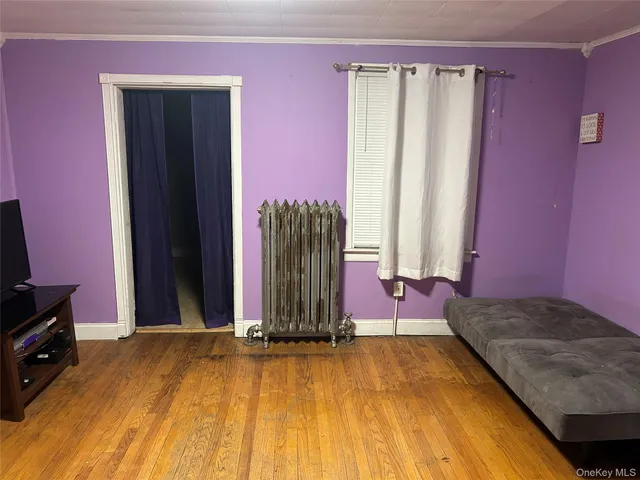 a view of a bedroom with wooden floor and a window