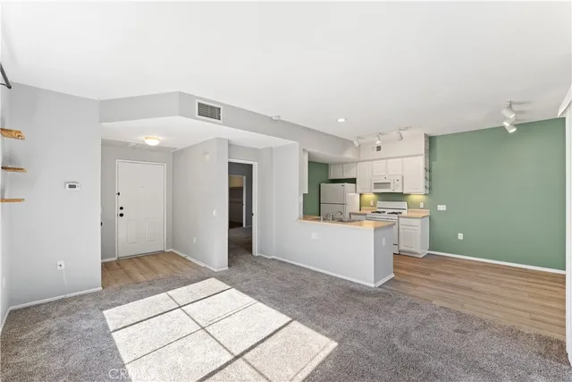 a view of a kitchen with refrigerator and white cabinets
