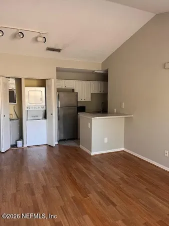 a view of a kitchen with refrigerator and wooden floor