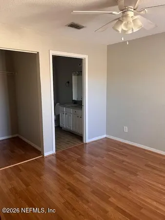 an empty room with wooden floor closet and windows
