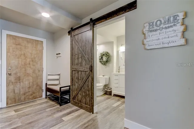 a view of a hallway with wooden floor and a bathroom