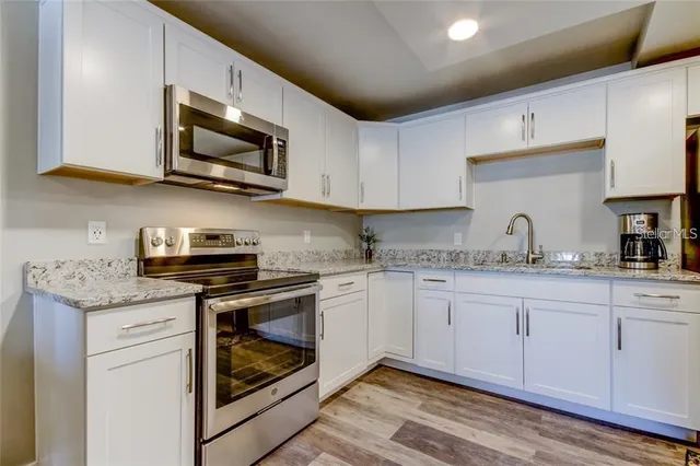 a kitchen with granite countertop white cabinets stainless steel appliances and sink