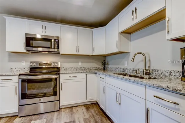 a kitchen with granite countertop white cabinets stainless steel appliances and a sink