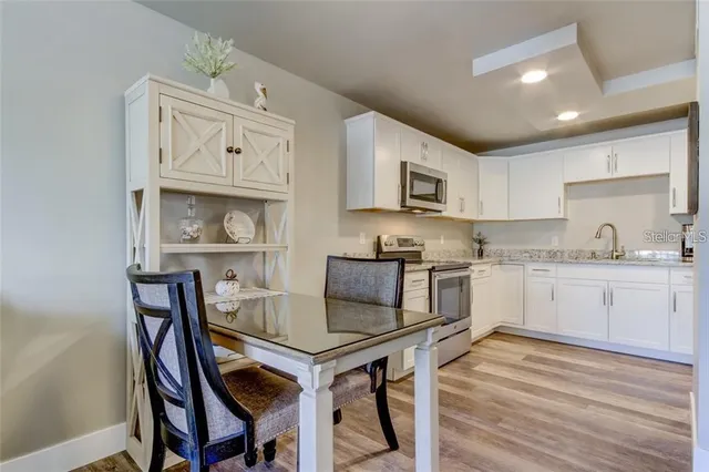 a kitchen with granite countertop a table chairs stove and cabinets