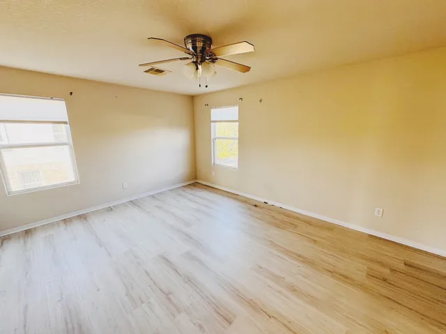 a view of empty room with wooden floor and fan