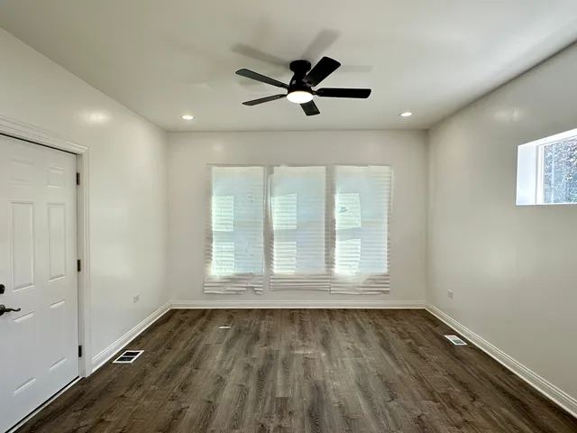a view of empty room with wooden floor and fan