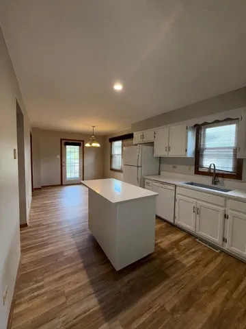 a large kitchen with kitchen island a sink dishwasher a stove and a refrigerator with wooden floor