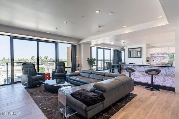 a living room with furniture large windows and wooden floor