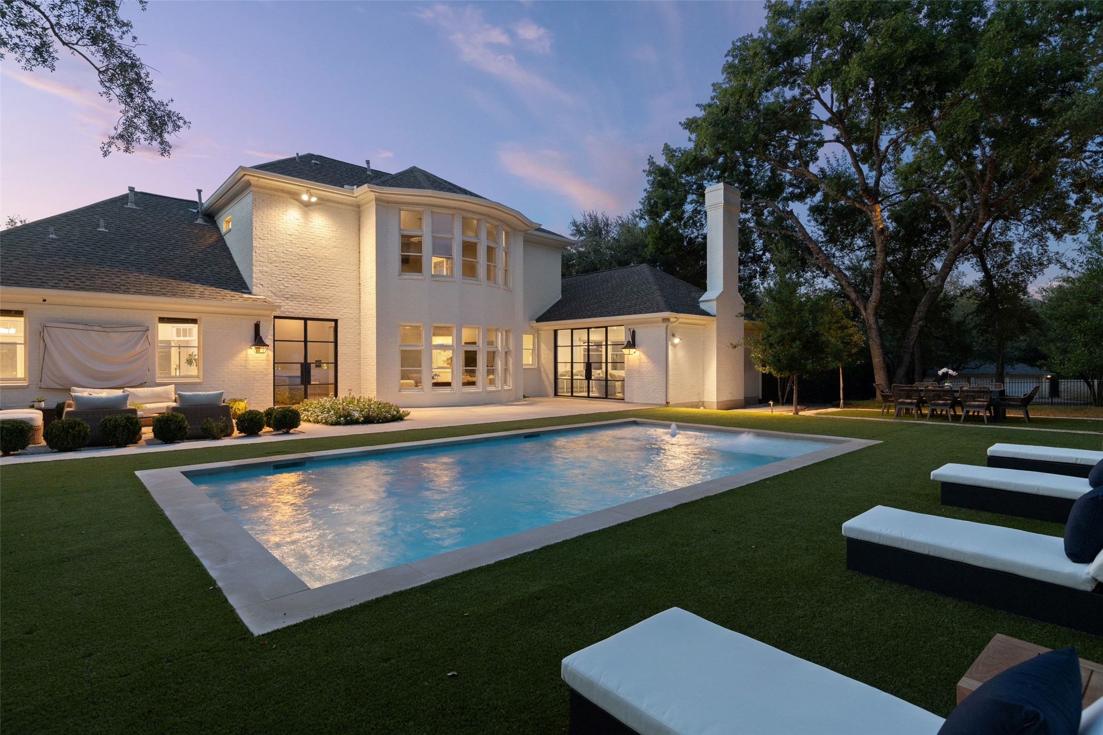 4201 Green Cliffs Road Austin, TX 78746 - Photo 33 of 40 Dusk lighting showcases the outdoor pool and lawn areas, creating an inviting setting for warm evening gatherings outdoors