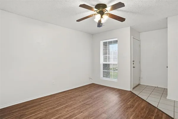 an empty room with wooden floor chandelier fan and windows