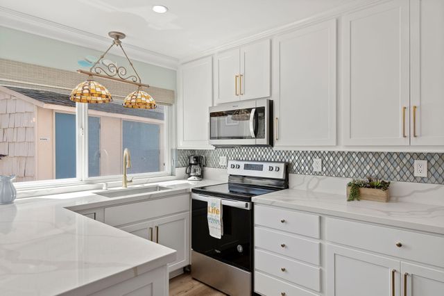a kitchen with cabinets appliances a sink and a window