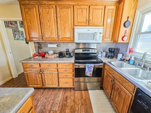a kitchen with stainless steel appliances granite countertop wooden cabinets a sink and dishwasher with wooden floor