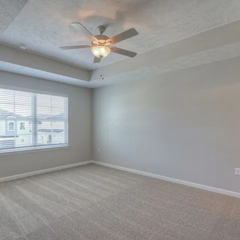 an empty room with a chandelier fan and windows