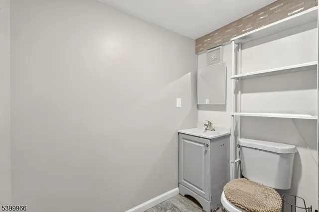 a bathroom with a toilet a sink and wooden floor