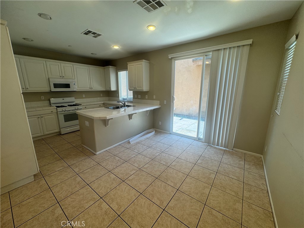 9757 Edenbrook Drive Riverside, CA 92503 - Photo 10 of 40 a kitchen with kitchen island granite countertop a sink a counter top space and cabinets