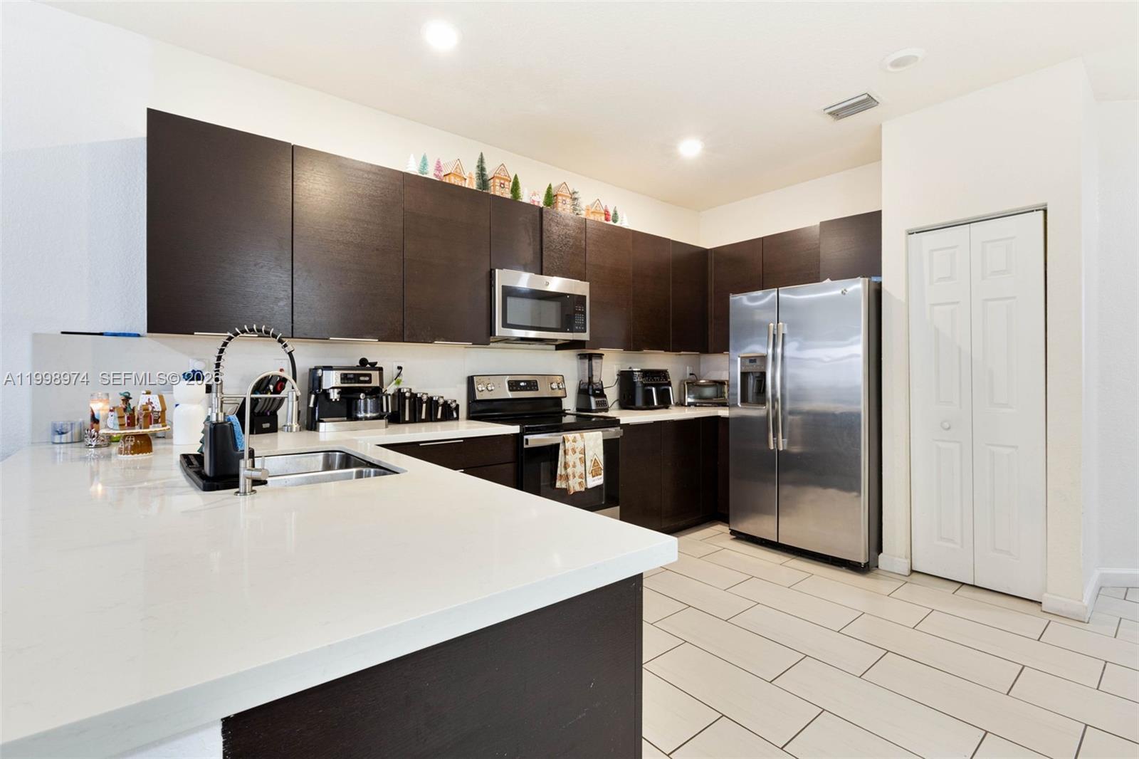 15070 Southwest 119TH Lane Miami, FL 33196 - Photo 6 of 30 a kitchen with stainless steel appliances a refrigerator sink and microwave