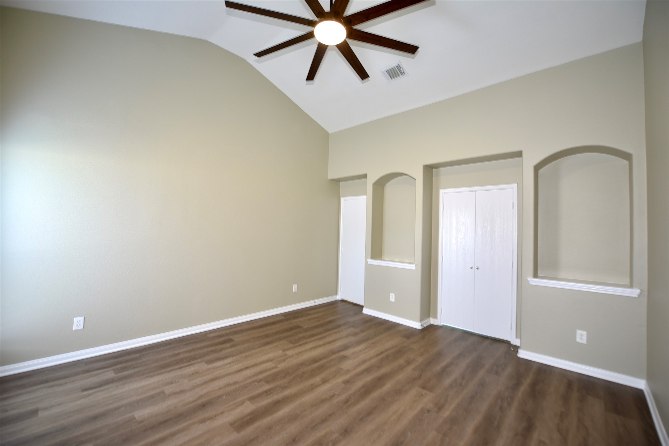 9611 Babbling Spring Court Tomball, TX 77375 - Photo 14 of 31 This room features a high ceiling with a modern fan, laminate wood flooring, and neutral walls. It includes built-in alcoves and a closet with double doors, offering a clean and spacious look.