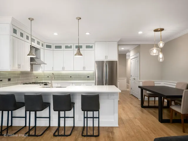 a kitchen with stainless steel appliances kitchen island granite countertop a dining table chairs and white cabinets