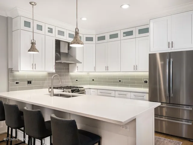 a kitchen with stainless steel appliances a sink a stove a refrigerator and white cabinets