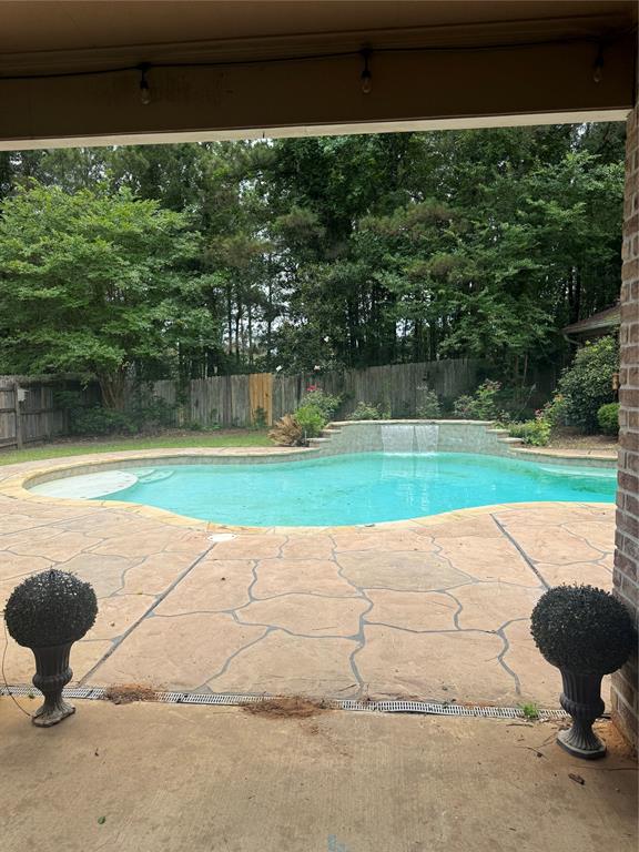 201 Woodhaven Drive Minden, LA 71055 - Photo 31 of 31 Outdoor swimming pool featuring a waterfall feature, flagstone-style patio, surrounding foliage, and a perimeter fence