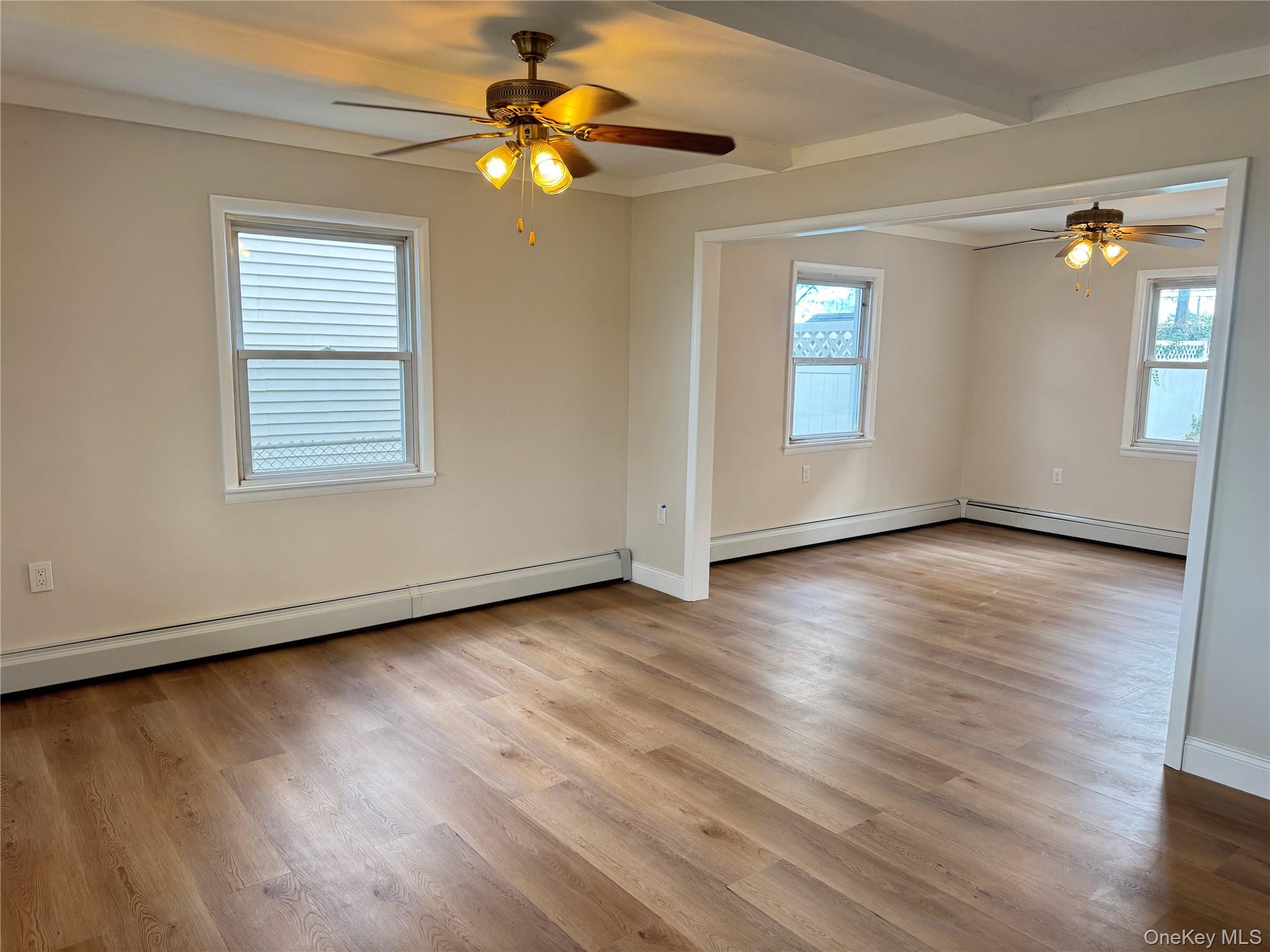 129 Spring Lane Levittown, NY 11756 - Photo 3 of 18 an empty room with wooden floor chandelier fan and windows