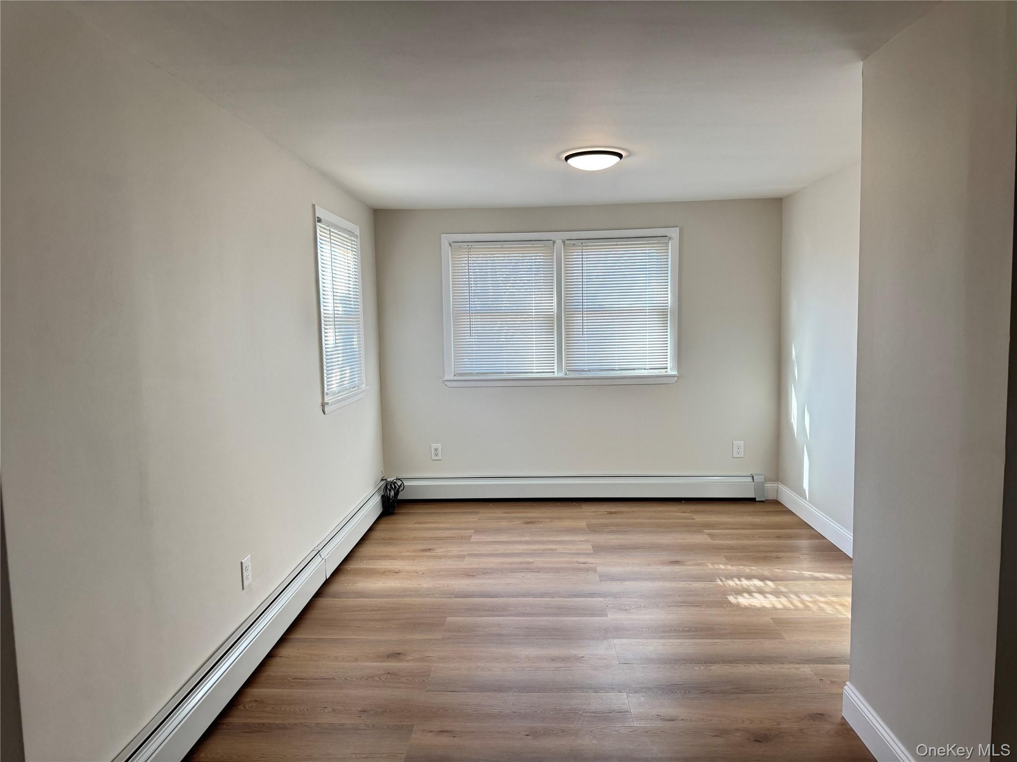 129 Spring Lane Levittown, NY 11756 - Photo 8 of 18 an empty room with wooden floor and windows