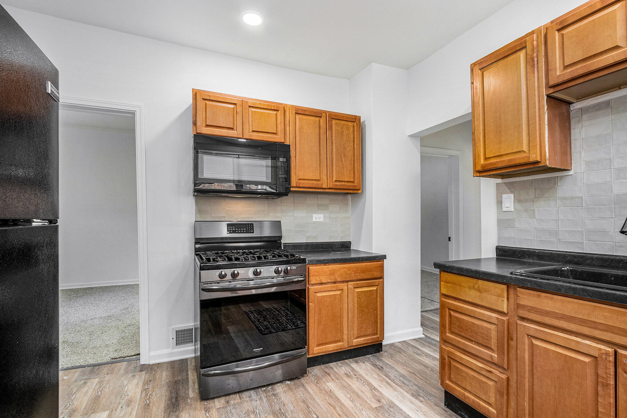1067 Polk Street Gary, IN 46402 - Photo 5 of 13 a kitchen with granite countertop wooden cabinets and a stove top oven