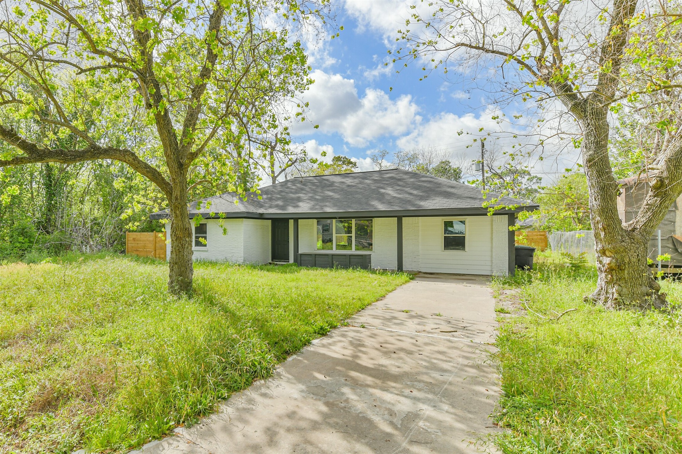 209 Leago Street Houston, TX 77022 - Photo 23 of 24 This charming single-story home features a welcoming façade with a modern black and white exterior. It is set on a spacious lot with mature trees and a lush green lawn, offering ample outdoor space. The driveway leads directly to the entrance, creating a convenient and inviting approach.