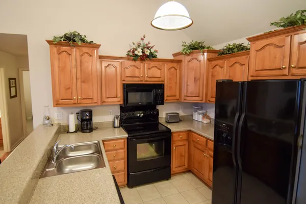 a kitchen with granite countertop a refrigerator stove and wooden cabinets