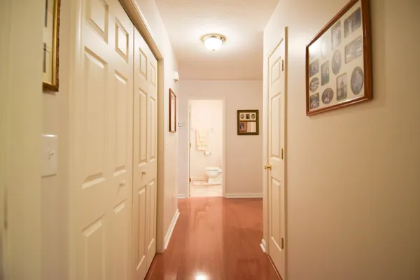 a view of a hallway with wooden floor and closet