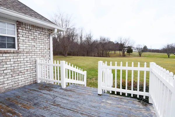 a view of a deck with wooden floor and fence next to a yard
