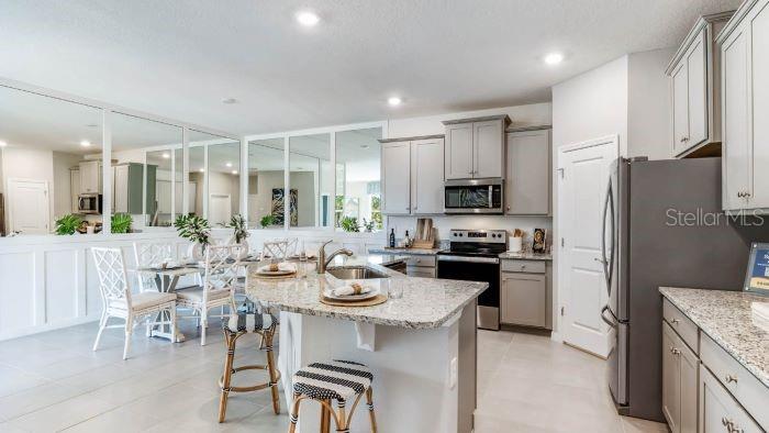 18391 Tavernside Trail Lakewood Ranch, FL 34211 - Photo 5 of 41 a kitchen with a refrigerator a stove a dining table and chairs