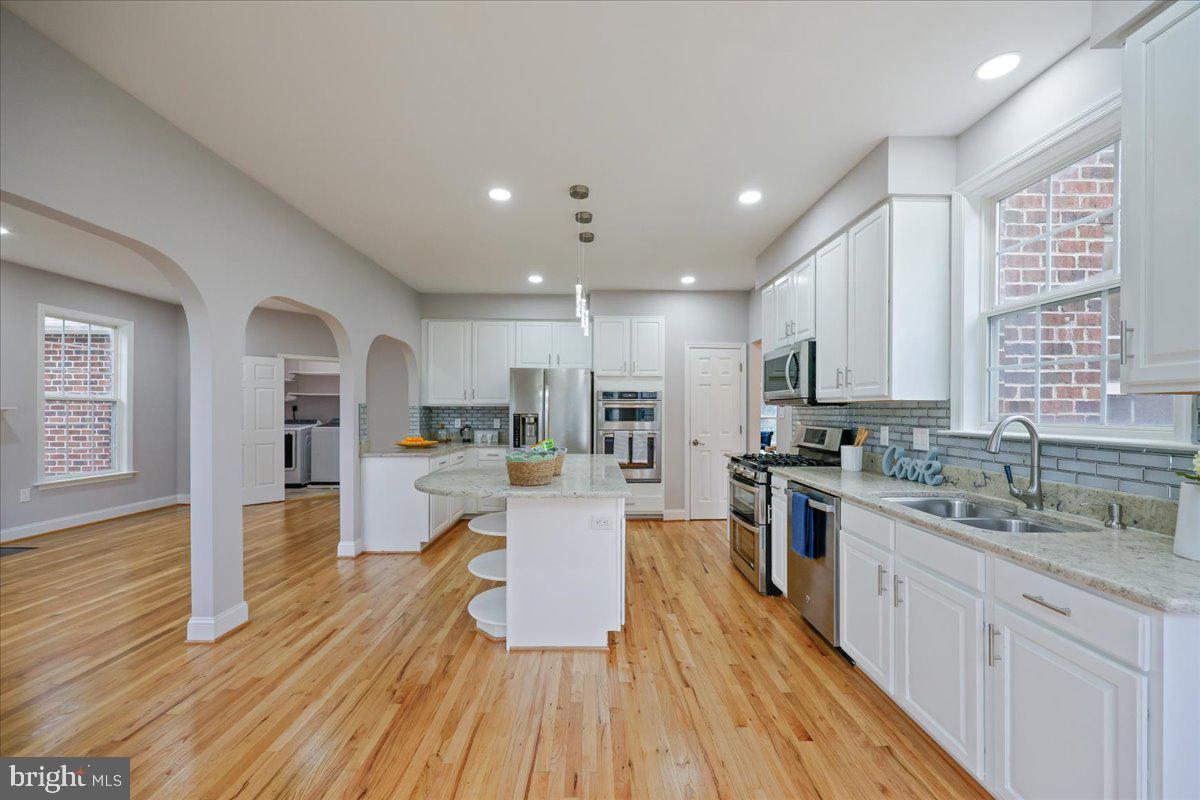 21712 Slidell Road Boyds, MD 20841 - Photo 12 of 32 a large kitchen with kitchen island wooden floors white cabinets and stainless steel appliances