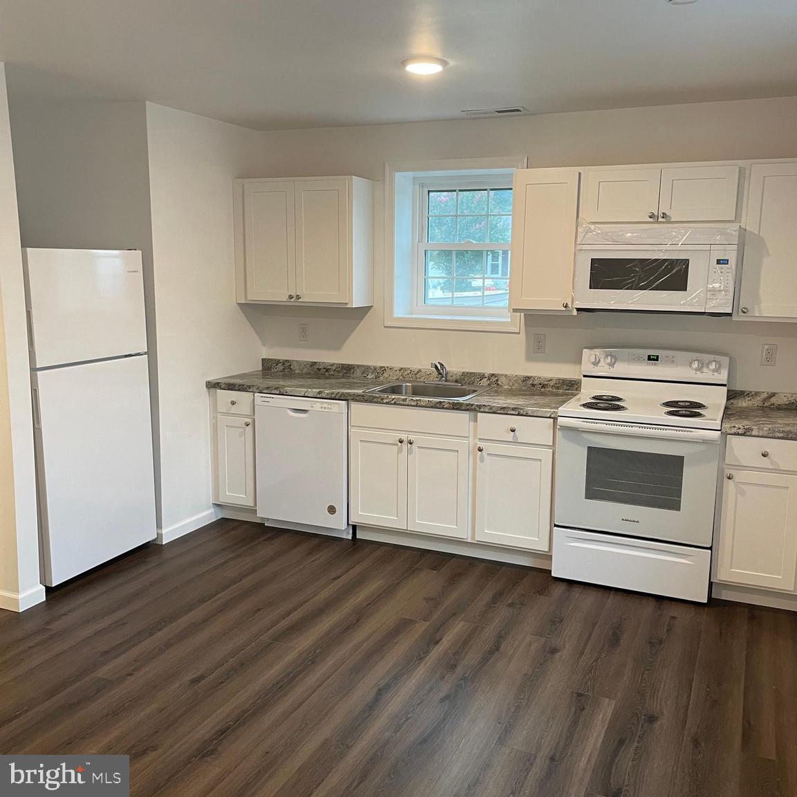 a kitchen with stainless steel appliances a white stove top oven cabinets and a wooden floor