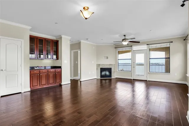 an empty room with wooden floor fireplace and windows