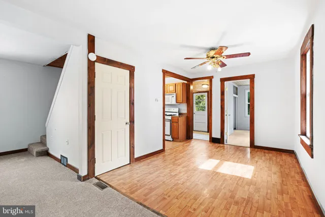 a view of an empty room with window and a kitchen