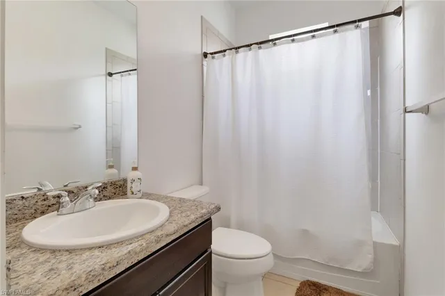 a bathroom with a granite countertop sink toilet and a mirror