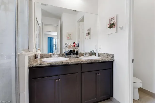 a bathroom with a granite countertop sink and a toilet