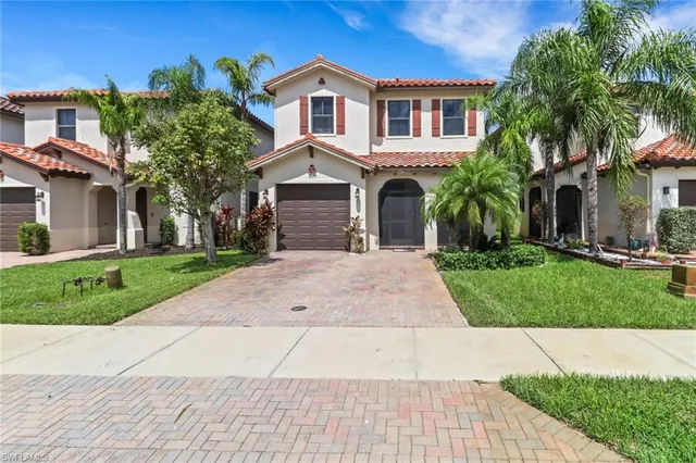 a front view of a house with a yard and potted plants