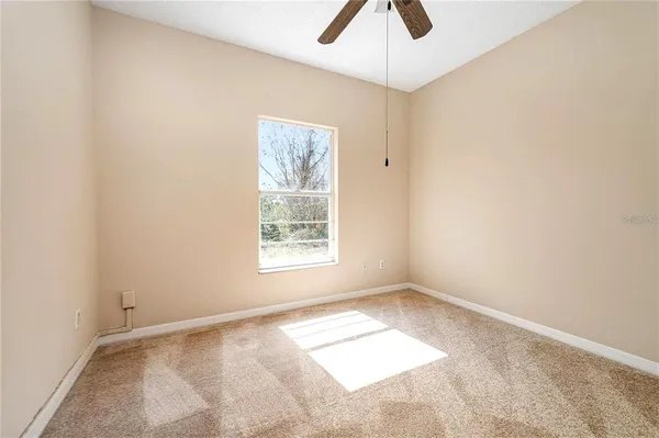 an empty room with a window and a fan