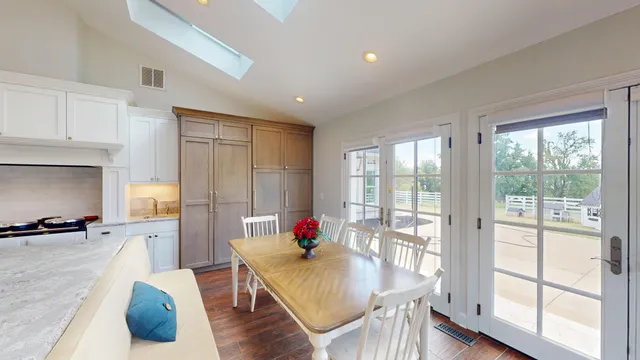 a kitchen with stainless steel appliances kitchen island granite countertop a sink dishwasher a dining table and chairs with wooden floor